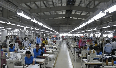 Factory workers in green uniforms at sewing stations